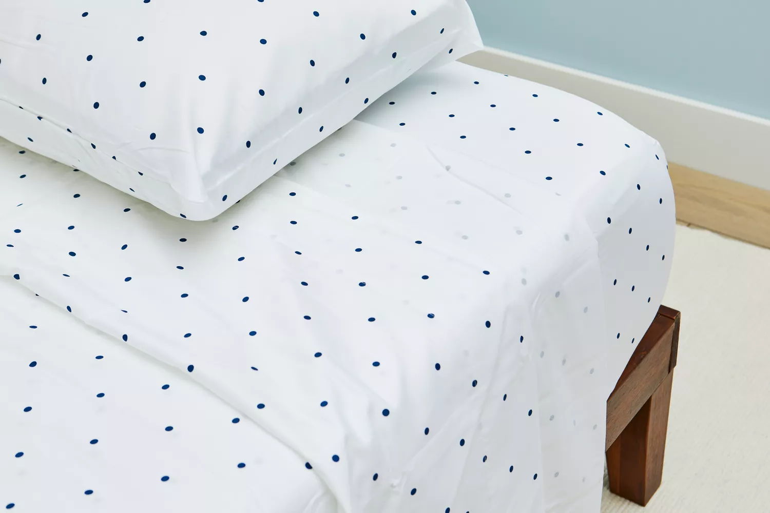 Closeup of a corner of a bed made with a California Design Den Cotton Sateen Sheet Set