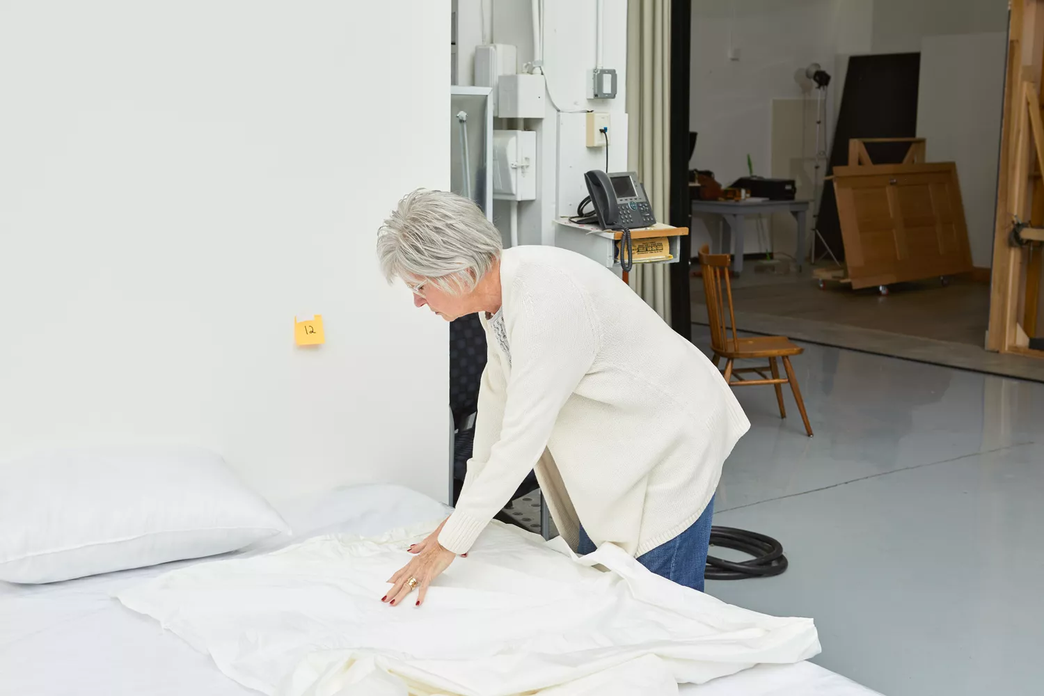 Person folding the Crane & Canopy 400 Thread Count Percale Cotton Sheet Set on a bed 