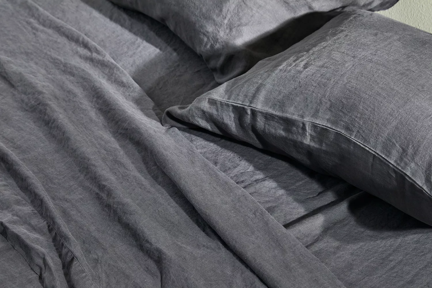 Closeup of the Quince European Linen Sheet Set with pillows on a bed 