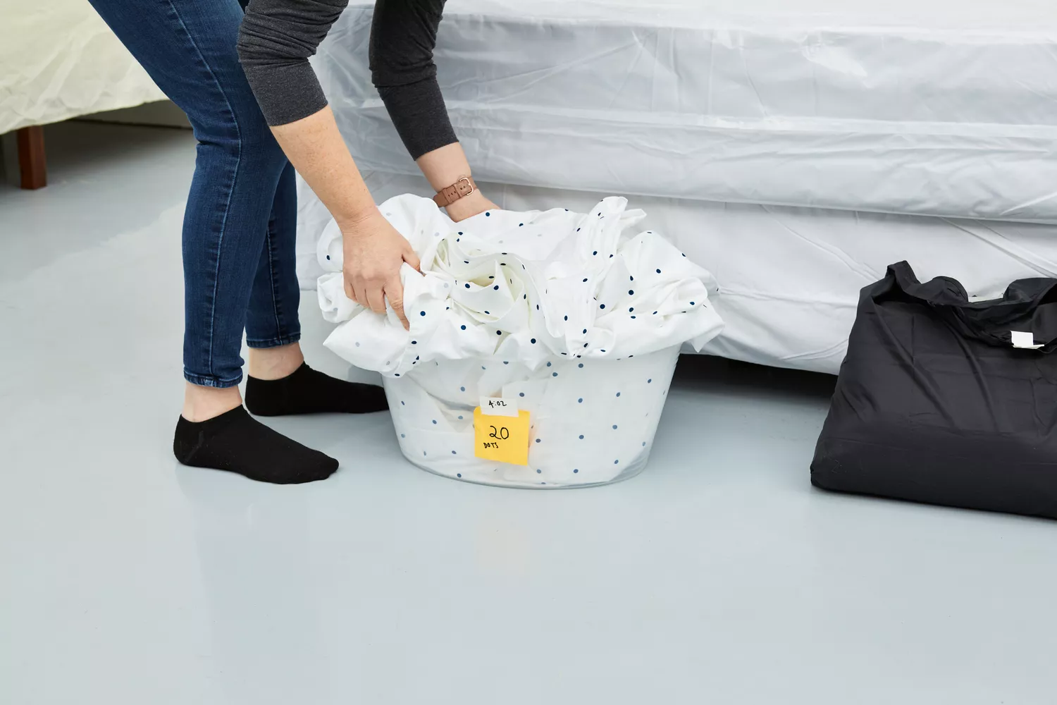 Person holding sheets from the California Design Den Cotton Sateen Sheet Set in a laundry basket 