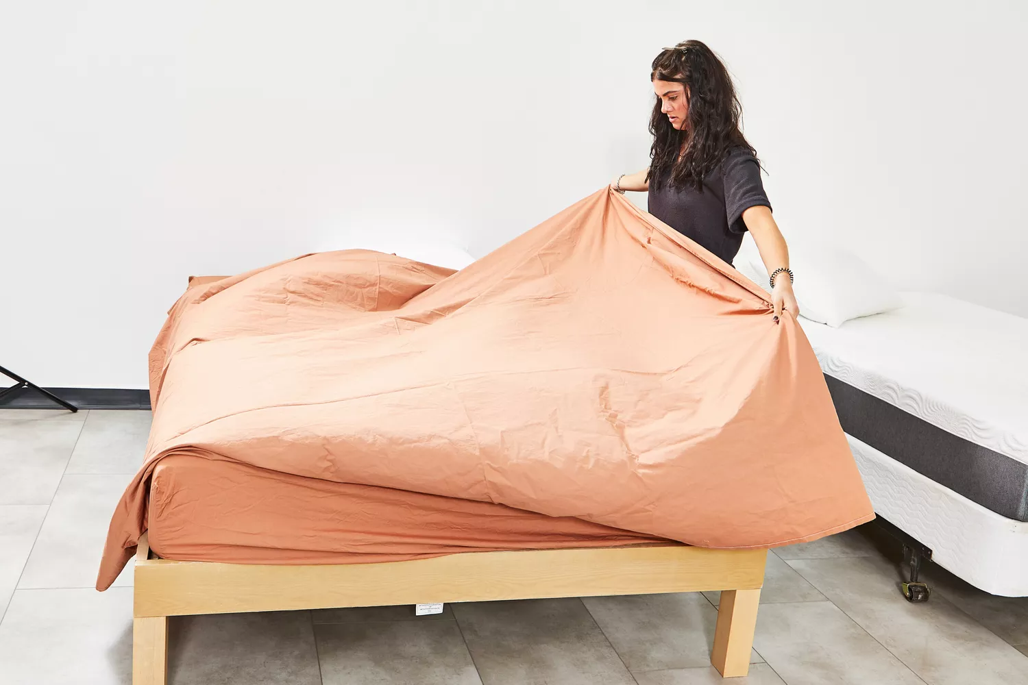 Women spreading West Elm Organic Washed Cotton Percale Sheet Set on bed
