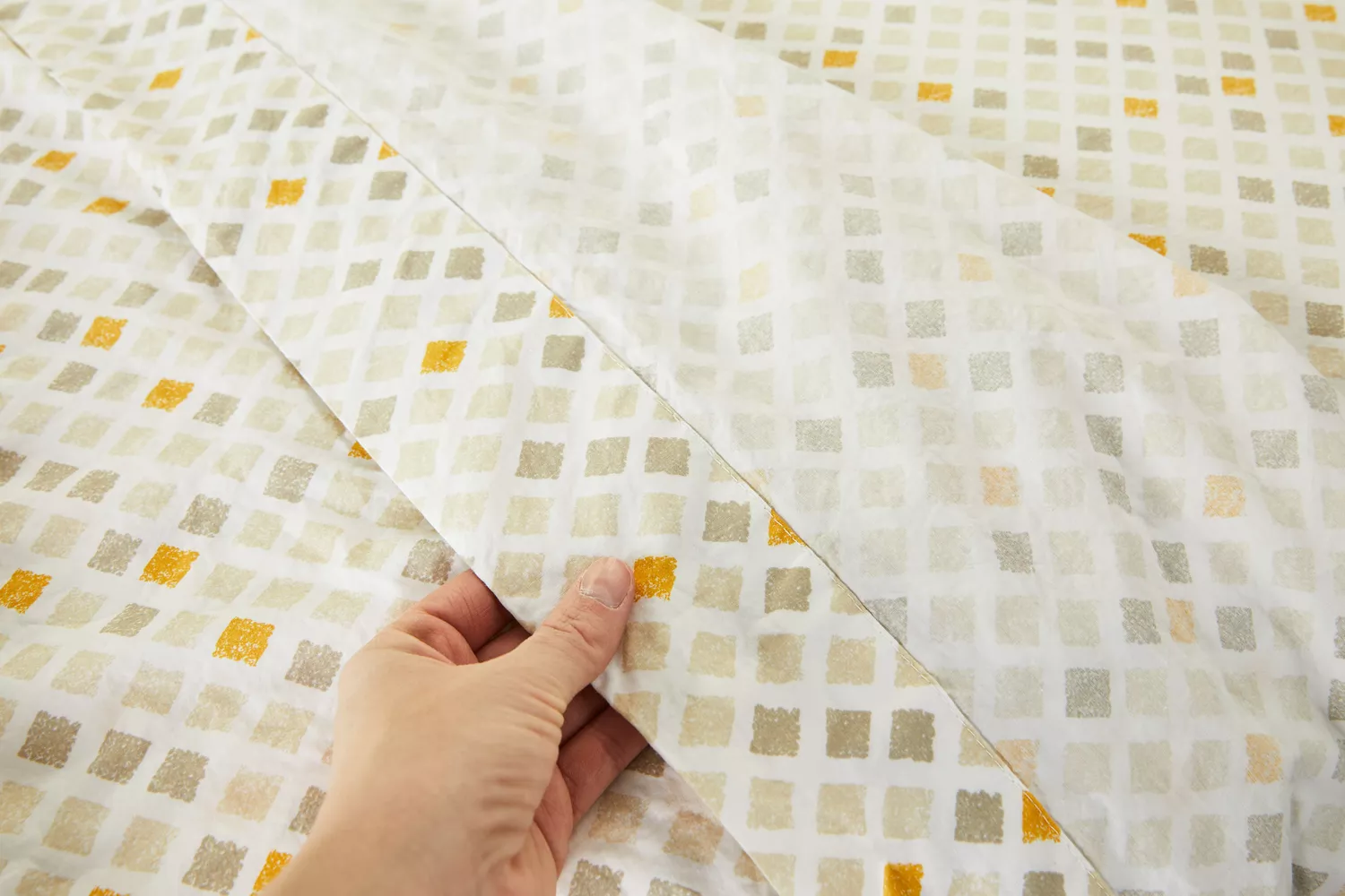 A person holding one part of the Feather & Stitch 100% Cotton Sheets
