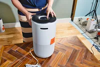 Person pushing button on top of the Levoit Core 400S Smart True HEPA Air Purifier