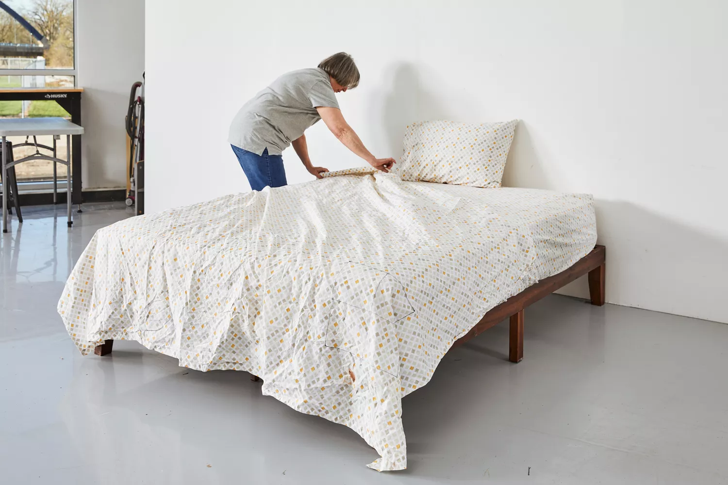 A person fixing a bed with the Feather & Stitch 100% Cotton Sheets