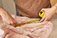 Person holding a measuring tape over a Linenwalas 100% Tencel Lyocell fitted bed sheet