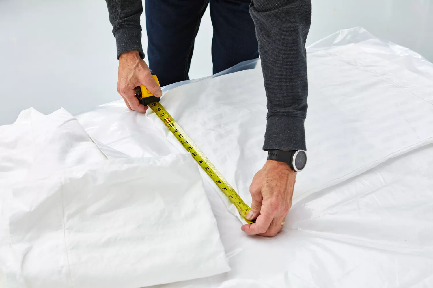 Person using measuring tape on Chateau Home Collection Egyptian Cotton pillowcase on bed